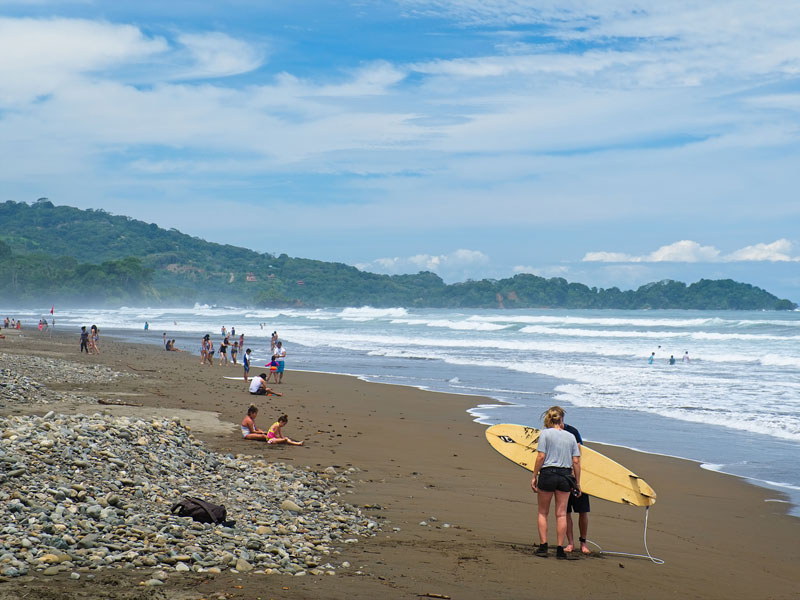 A group of people standing on top of a sandy beach.
